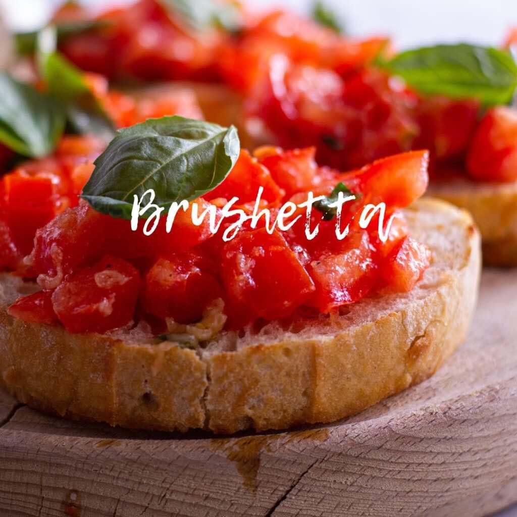 bruschetta on a wooden plate with basil leaves on top