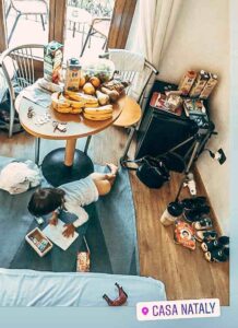 boy in a hotel room growing a picture, there is a table and lots of food on it.